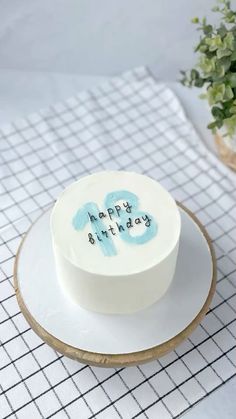 a birthday cake with the words happy birthday on it sitting on a plate next to a potted plant