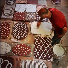 a man is decorating cookies with chocolate icing and white dots on the ground