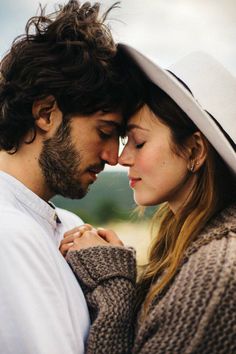 a man and woman standing next to each other in front of the camera with their eyes closed