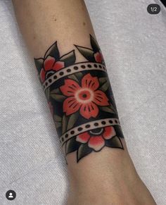 a woman's arm with a red flower tattoo on it and a ribbon around the wrist