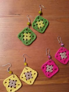 four crocheted square shaped earrings sitting on top of a wooden table