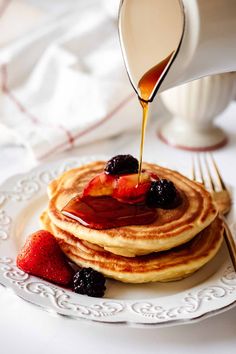 pancakes on a plate with syrup being poured onto them