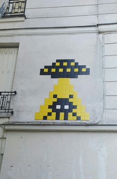 a yellow and black fire hydrant is painted on the side of a white building