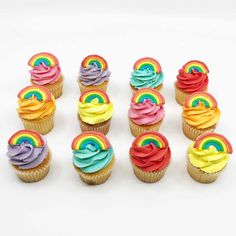 several cupcakes with rainbow frosting on them are arranged in a row against a white background