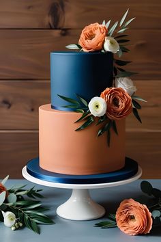 a three tiered cake with flowers on top and greenery around the edges, sitting on a table