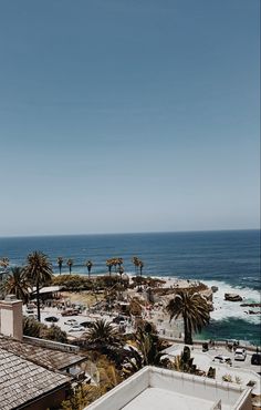 an ocean view with palm trees in the foreground and buildings on the other side