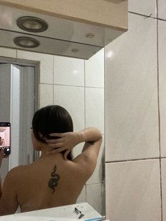 a person taking a selfie in front of a bathroom mirror with their back turned to the camera