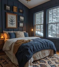 a bedroom with dark blue walls and white bedding is lit by two candles on the nightstands