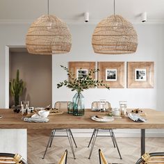 a dining room table with chairs, plates and vases on it in front of two framed pictures