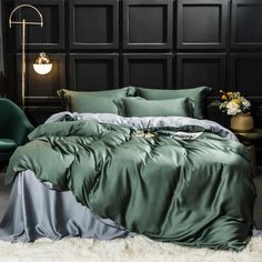 a bed with green sheets and pillows in a room next to a wall mounted lamp