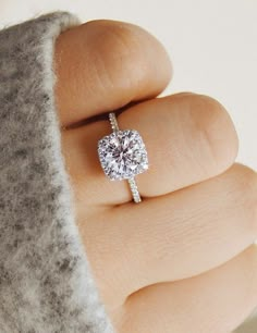 a close up of a person's hand with a diamond ring on their finger