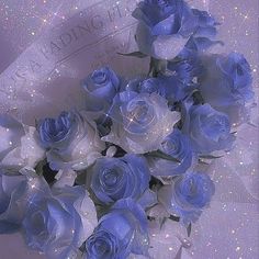 a bouquet of blue roses sitting on top of a white cloth covered tablecloth with sparkles in the background