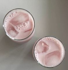 two glasses filled with pink liquid on top of a table