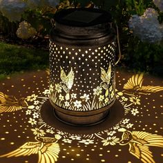 a lit up lantern sitting on top of a table next to flowers and grass in the background