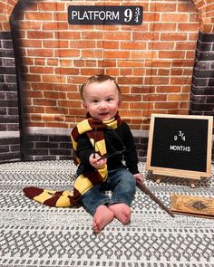 a baby sitting on the floor next to a harry potter sign