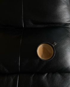 a cup of coffee sitting on top of a black leather couch