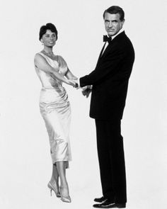 a man and woman standing next to each other in front of a white background holding hands