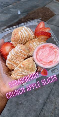 a person holding up a plastic container with strawberries and cream on it next to a bowl of fruit