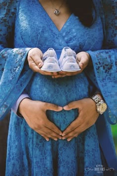 a pregnant woman holding two baby shoes in her hands