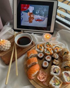 sushi and chopsticks on a wooden plate next to a television