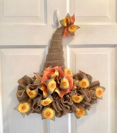 a burlap wreath with sunflowers and orange flowers hanging on a white door