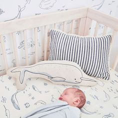 a baby is sleeping in his crib next to a pillow and stuffed toy whale