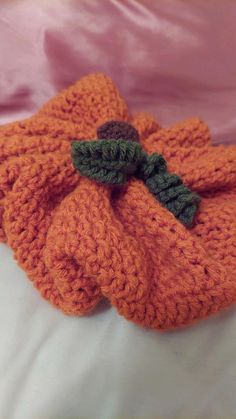 an orange knitted pumpkin on a bed