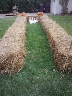 an image of some hay bales in the grass with pumpkins on them and people standing around