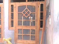 a cat sitting on the ground in front of a wooden door with glass panes