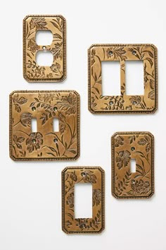 three decorative switch plates and one outlet cover in wood with floral designs on the sides