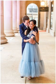 a man and woman hugging each other in front of pillars with columns on either side