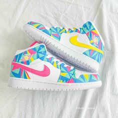 a pair of colorful nike shoes on top of a white sheet