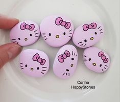 hello kitty painted rocks on a plate with the words happy stones written below them in pink