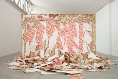 a pile of paper sitting on top of a floor next to a white wall in a room