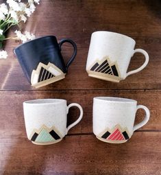 three coffee mugs sitting on top of a wooden table