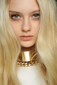 a woman with blonde hair wearing a gold choker