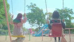 two children playing on swings in a park