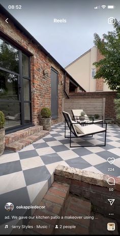 a black and white checkerboard patio with furniture on it, next to a brick building