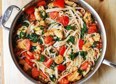 a pan filled with pasta and vegetables on top of a wooden table