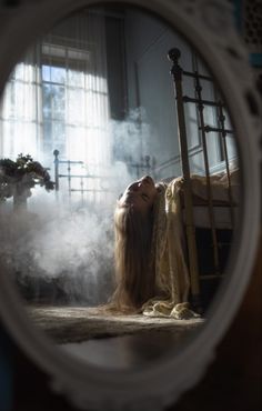 a woman laying on the floor in front of a mirror with steam coming out of it