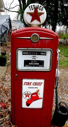 an old fashioned gas pump sitting on top of leaves