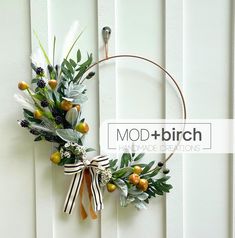 a wreath hanging on the side of a white wall with flowers and leaves in it