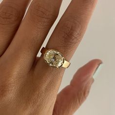 a woman's hand with a ring on it that has an oval shaped diamond in the center