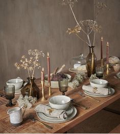 a wooden table topped with dishes and candles