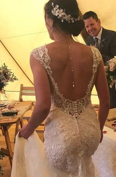 the back of a bride's dress as she stands in front of a table