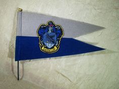 a blue and grey flag with a hogwart's crest on the front is laying on a white surface