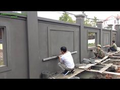 two men are working on the side of a building that's being built with concrete