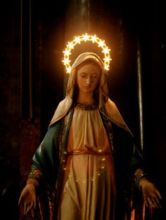 a statue of the virgin mary holding a wreath of lights