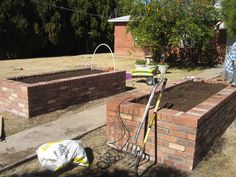 a man standing in front of a brick wall next to a pile of dirt on the ground