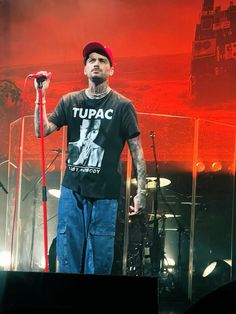 a man standing on top of a stage holding a red microphone in front of him